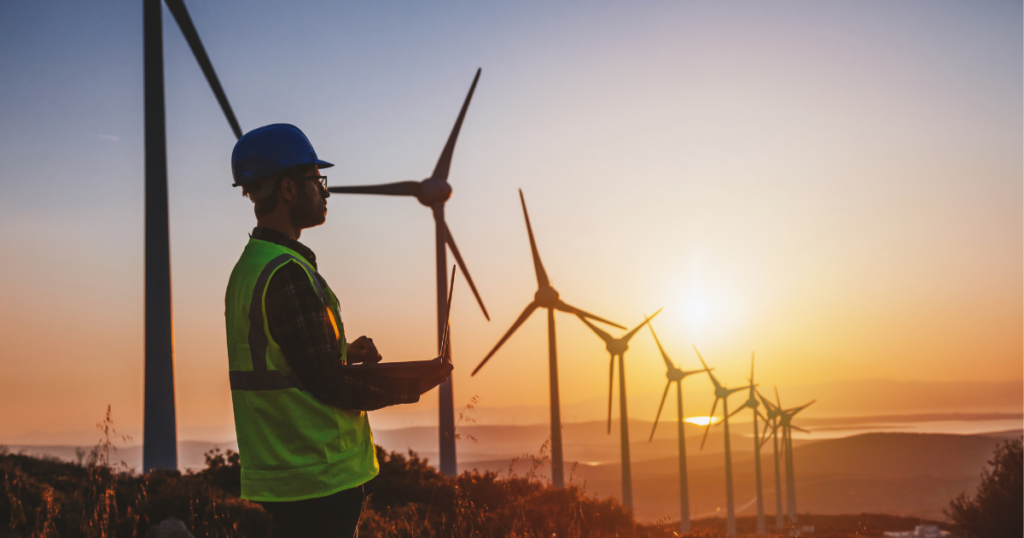 man in a hard hat overlooking wind turbines.