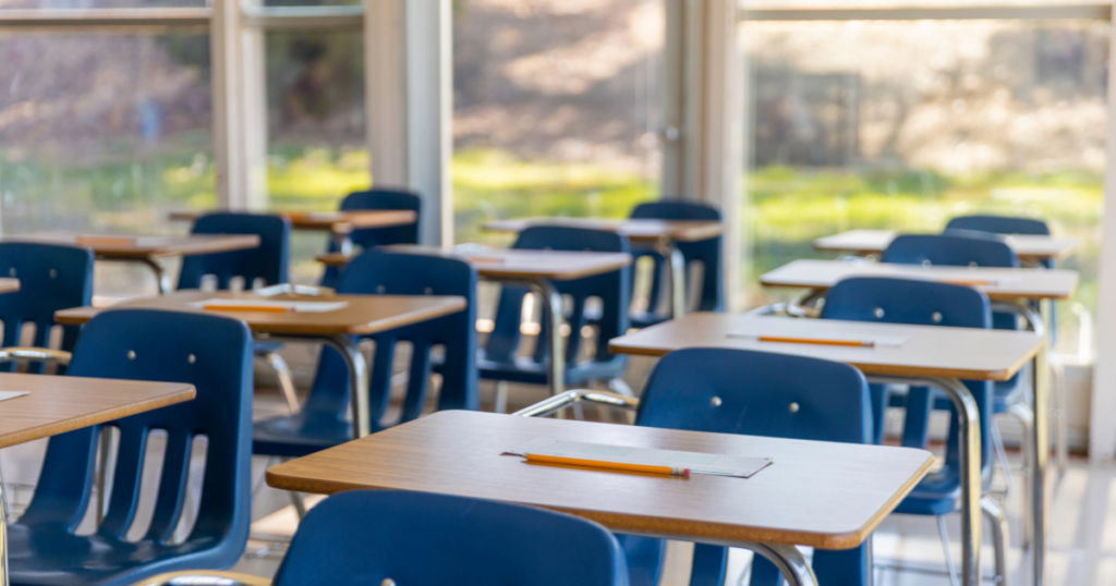 Classroom filled with blue chairs and wooden desks.